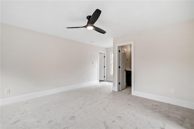 empty room featuring a ceiling fan, baseboards, and light colored carpet