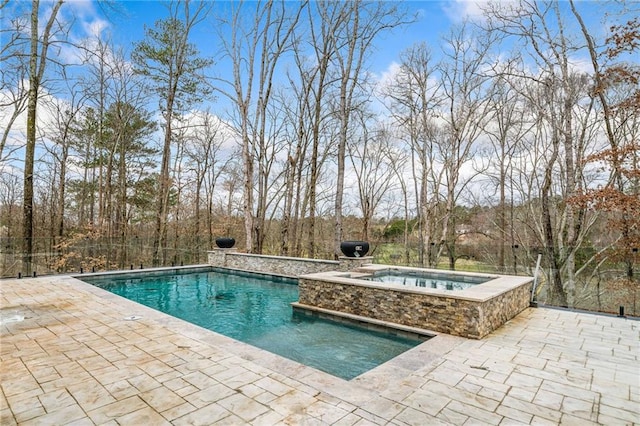outdoor pool with a patio area and an in ground hot tub