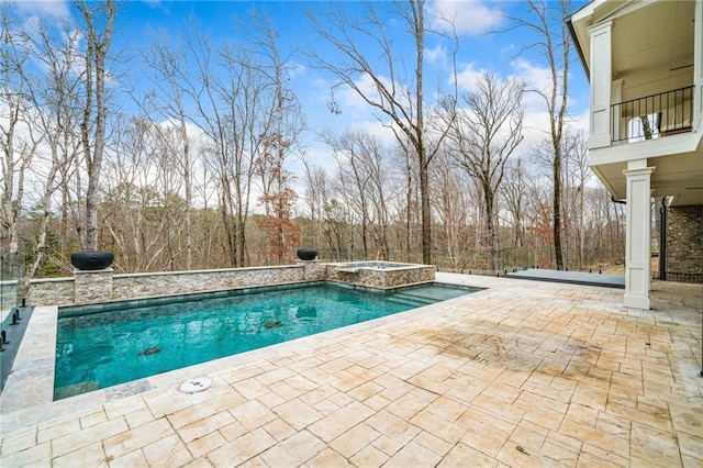pool with a patio area and an in ground hot tub