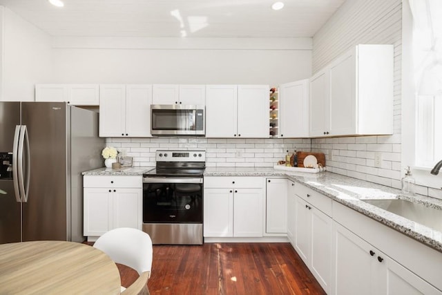 kitchen featuring stainless steel appliances, white cabinets, dark wood finished floors, tasteful backsplash, and recessed lighting