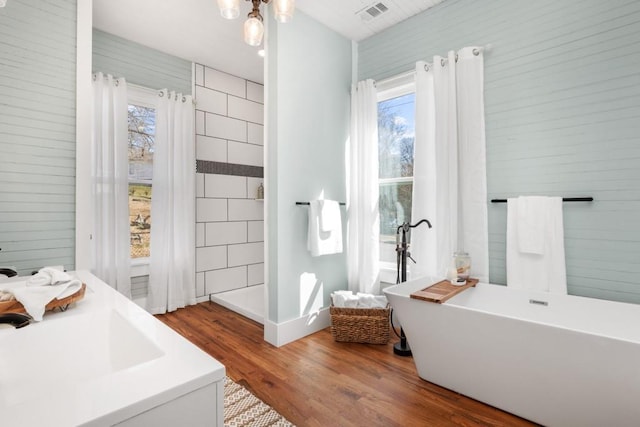 full bathroom with wood finished floors, plenty of natural light, a freestanding tub, and a shower