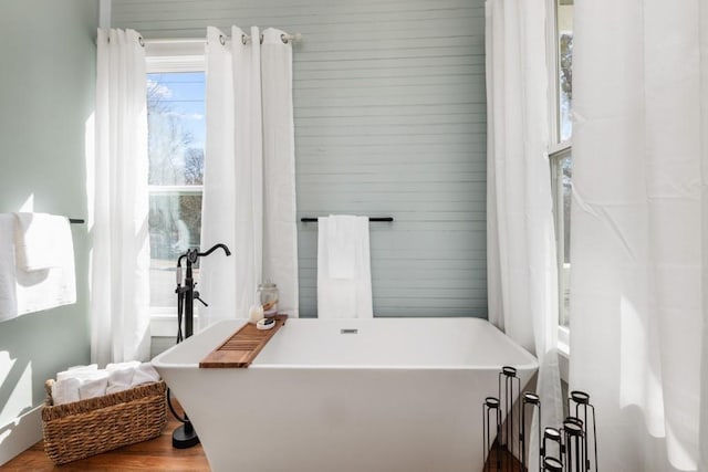 full bathroom with a freestanding bath and wood finished floors