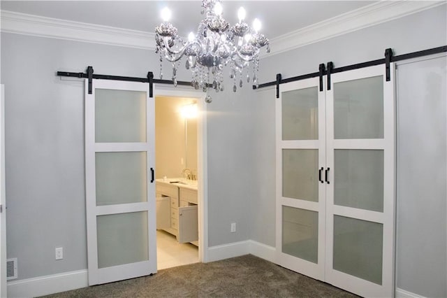 unfurnished bedroom featuring a notable chandelier, ensuite bath, a barn door, and carpet floors