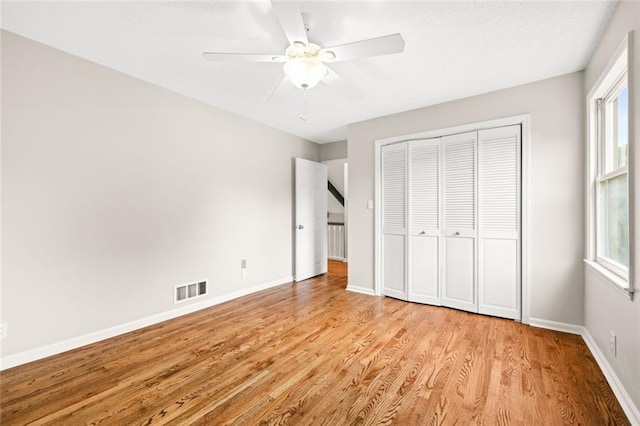 unfurnished bedroom featuring a closet, light hardwood / wood-style floors, ceiling fan, and multiple windows