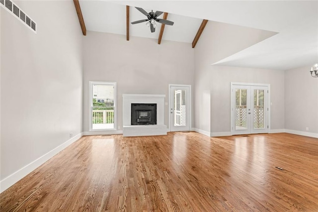 unfurnished living room with a wealth of natural light, light hardwood / wood-style floors, and beamed ceiling