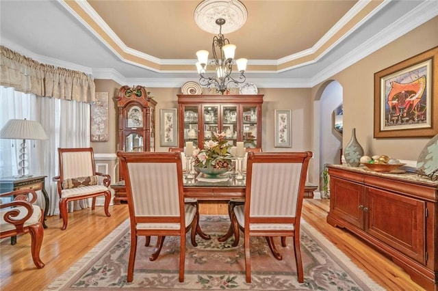 580 River Valley Dr, Dacula, GA 30019 - dining room with a chandelier, a raised ceiling, light wood-style flooring, arched walkways, and ornamental molding