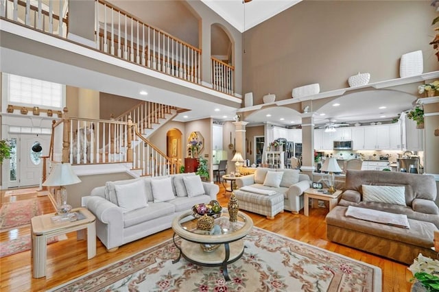 580 River Valley Dr, Dacula, GA 30019 - living room featuring a high ceiling, ceiling fan, light wood-type flooring, stairway, and ornate columns