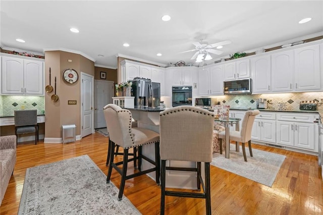 580 River Valley Dr, Dacula, GA 30019 - kitchen with oven, stainless steel microwave, fridge with ice dispenser, crown molding, and a kitchen bar