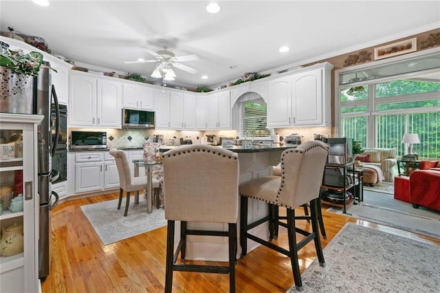 580 River Valley Dr, Dacula, GA 30019 - kitchen featuring stainless steel appliances, a breakfast bar, white cabinets, decorative backsplash, and ornamental molding