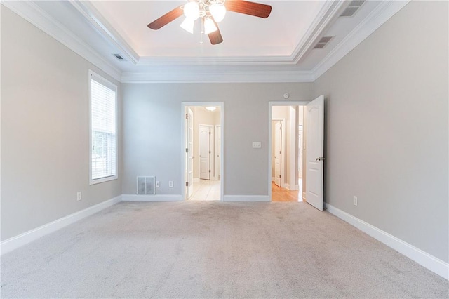 unfurnished bedroom with a raised ceiling, ceiling fan, light colored carpet, and ornamental molding