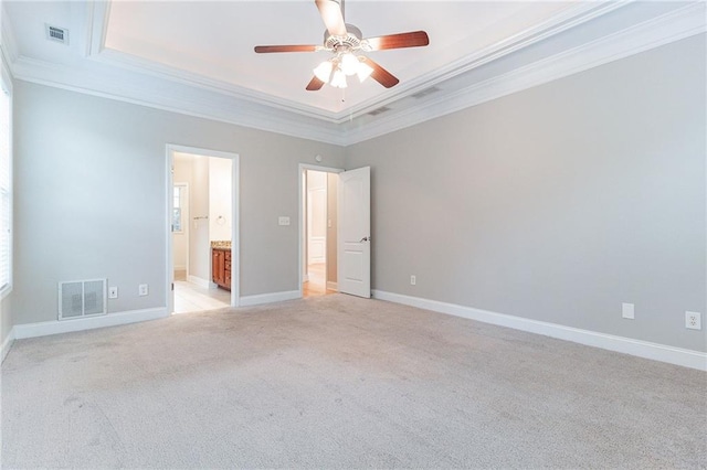 unfurnished bedroom featuring light carpet, connected bathroom, a raised ceiling, and ceiling fan