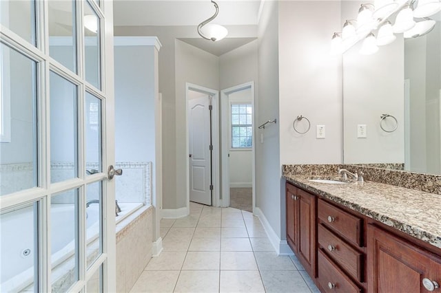 bathroom with tile patterned flooring, vanity, tiled tub, and a notable chandelier