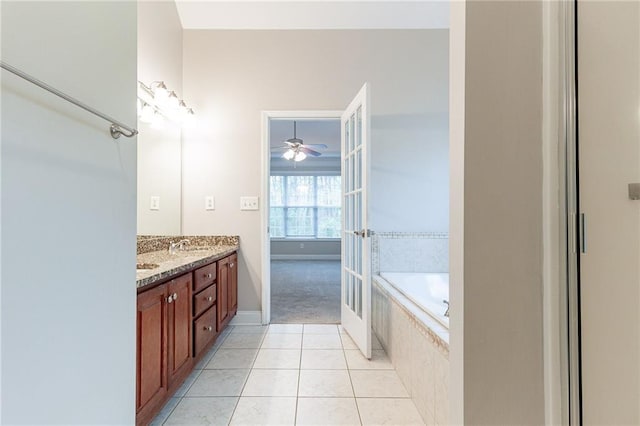 bathroom with tile patterned floors, vanity, ceiling fan, and tiled tub