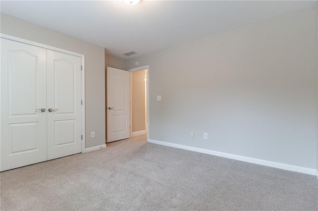 unfurnished bedroom with a closet and light colored carpet