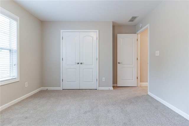 unfurnished bedroom with a closet and light colored carpet