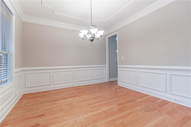 spare room with light hardwood / wood-style flooring, crown molding, and a notable chandelier