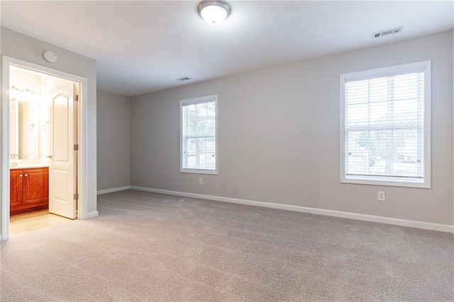 unfurnished bedroom with light carpet and ensuite bathroom