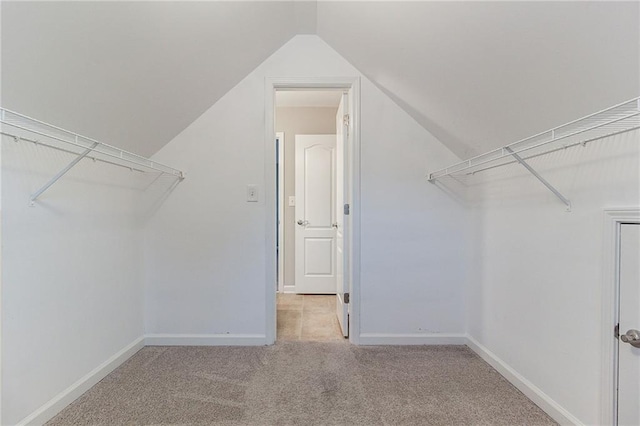 spacious closet with light colored carpet and vaulted ceiling