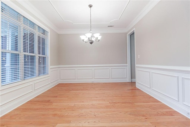 unfurnished dining area with light wood-type flooring, an inviting chandelier, and ornamental molding