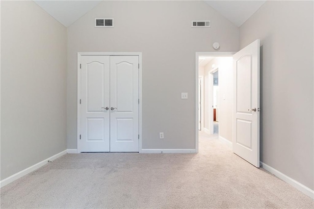 unfurnished bedroom with light colored carpet, high vaulted ceiling, and a closet