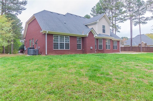 rear view of property with cooling unit and a lawn