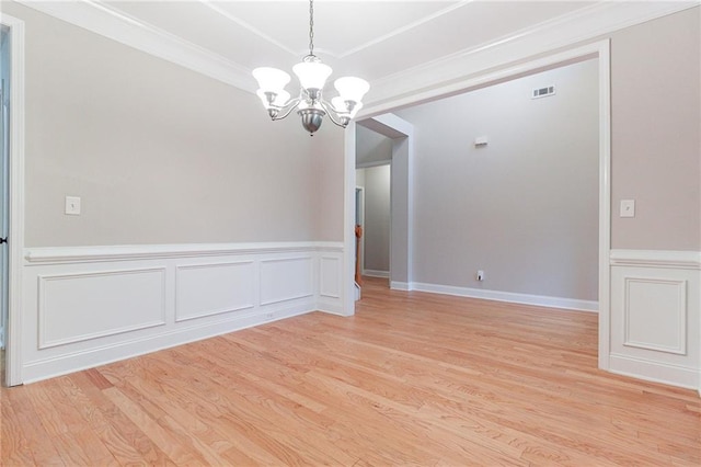 empty room with a chandelier, light wood-type flooring, and crown molding