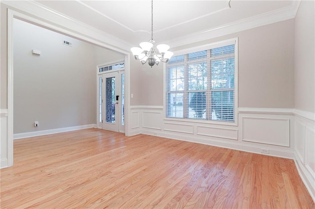 spare room with light hardwood / wood-style floors, an inviting chandelier, and ornamental molding