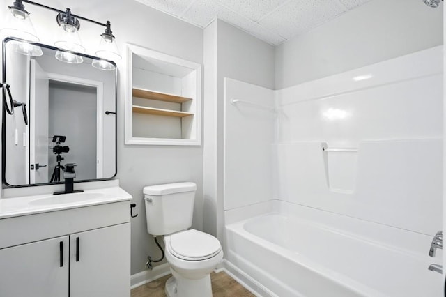 bathroom featuring bathtub / shower combination, vanity, toilet, a drop ceiling, and wood finished floors