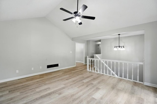 spare room featuring baseboards, ceiling fan with notable chandelier, light wood-type flooring, and lofted ceiling
