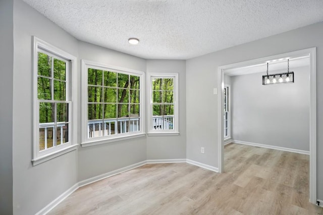 unfurnished room featuring baseboards, a textured ceiling, and wood finished floors