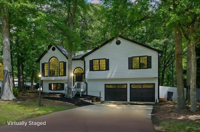 bi-level home featuring fence, an attached garage, and driveway