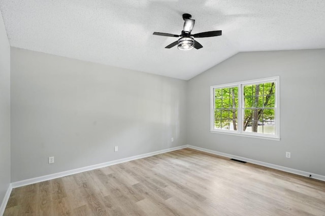 empty room with visible vents, light wood-type flooring, a textured ceiling, a ceiling fan, and vaulted ceiling
