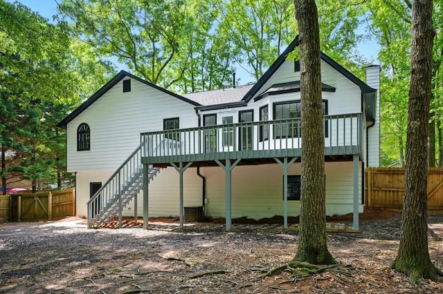 rear view of house with a chimney, a wooden deck, central AC unit, fence, and stairs