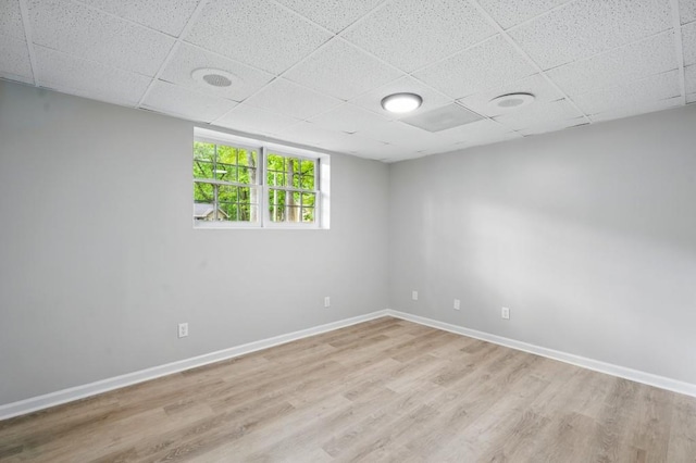 unfurnished room with baseboards, light wood-style flooring, and a paneled ceiling