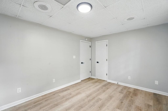 unfurnished room with baseboards, a paneled ceiling, and light wood-type flooring
