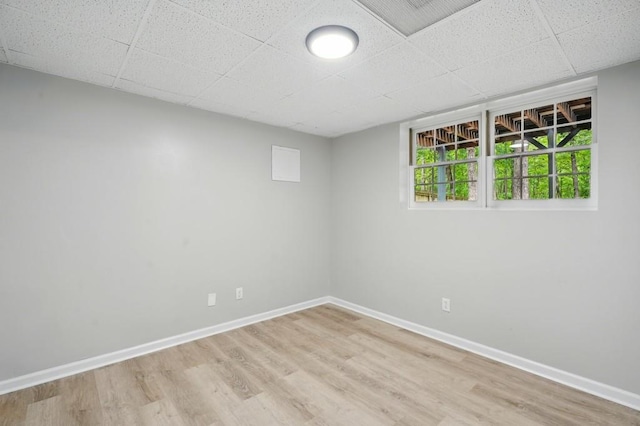 unfurnished room with baseboards, a drop ceiling, and wood finished floors
