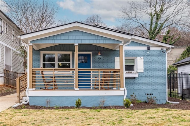 bungalow with a porch, brick siding, fence, crawl space, and a front yard