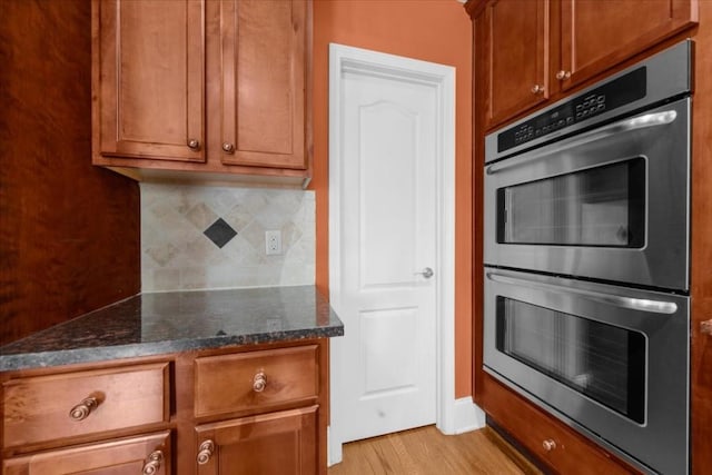 3086 Frazier Walk, Decatur, GA 30033 - kitchen featuring double oven, tasteful backsplash, dark stone countertops, light wood-style floors, and brown cabinetry