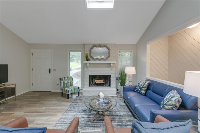 living room featuring light hardwood / wood-style floors, a brick fireplace, a healthy amount of sunlight, and vaulted ceiling