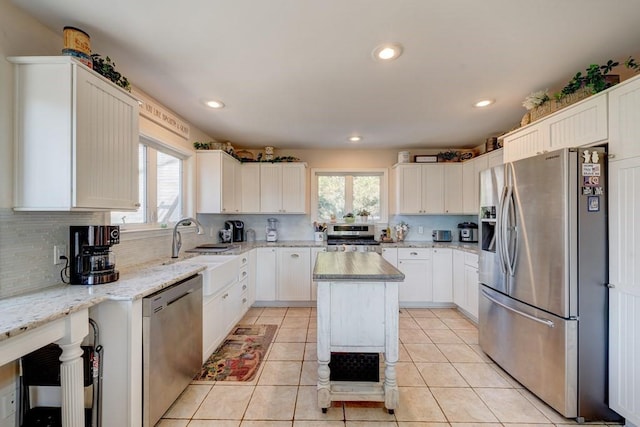 kitchen with white cabinetry, appliances with stainless steel finishes, a center island, and light stone countertops