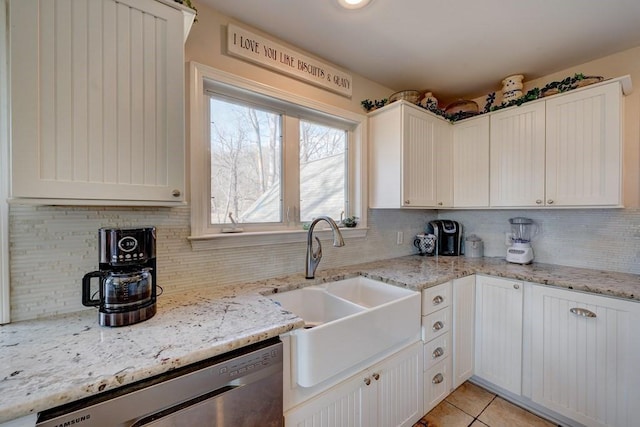 kitchen with sink, light stone countertops, white cabinets, light tile patterned flooring, and stainless steel dishwasher