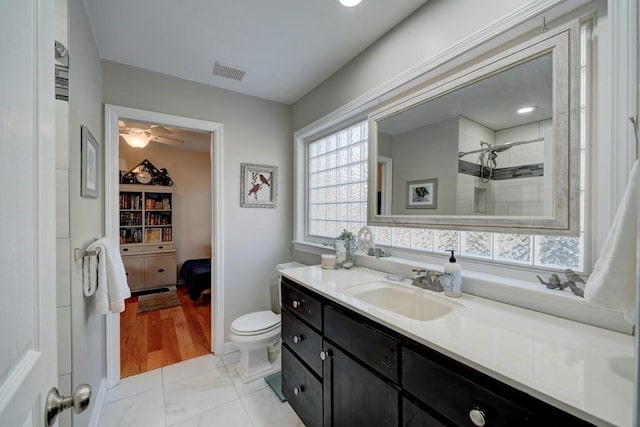 bathroom featuring tiled shower, vanity, and toilet