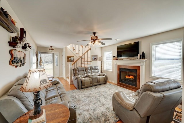 living room with a tile fireplace, a healthy amount of sunlight, ceiling fan, and light hardwood / wood-style floors