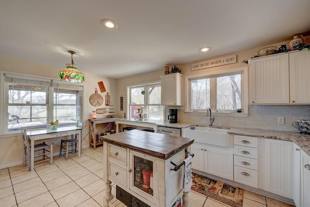 kitchen with pendant lighting, sink, white cabinetry, tasteful backsplash, and wood counters