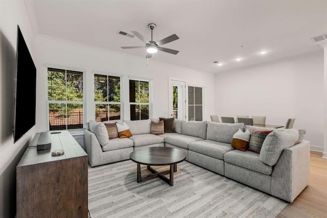 living room with a wealth of natural light, light wood-type flooring, ceiling fan, and visible vents