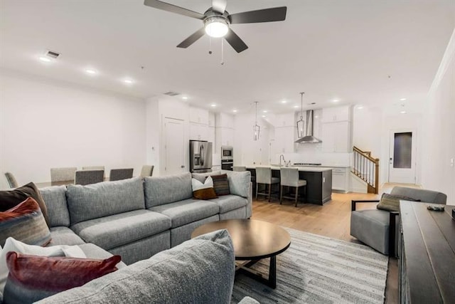 living area with visible vents, stairway, recessed lighting, a ceiling fan, and light wood-style flooring