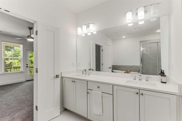 full bath with double vanity, a sink, ceiling fan, and a shower stall