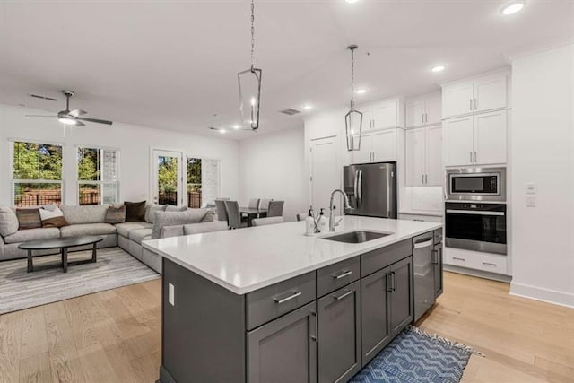 kitchen with a sink, appliances with stainless steel finishes, white cabinets, and light countertops