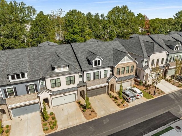 view of front of house featuring an attached garage, driveway, and a shingled roof
