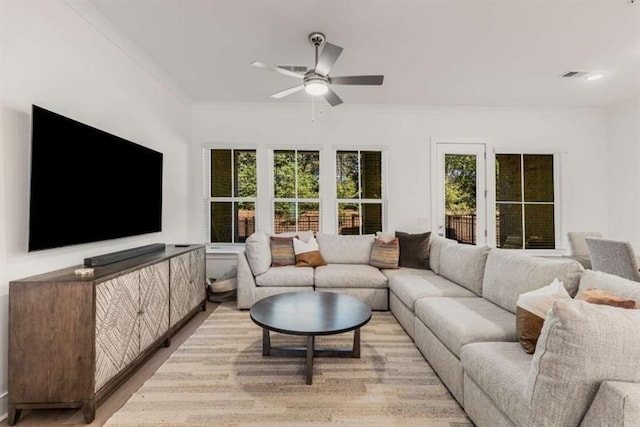 living area with visible vents, a ceiling fan, a healthy amount of sunlight, and ornamental molding